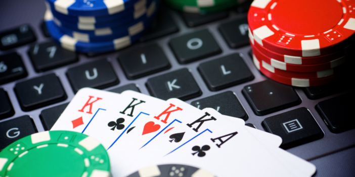 Een toetsenbord van laptop met daarop kaarten en pokermuntjes