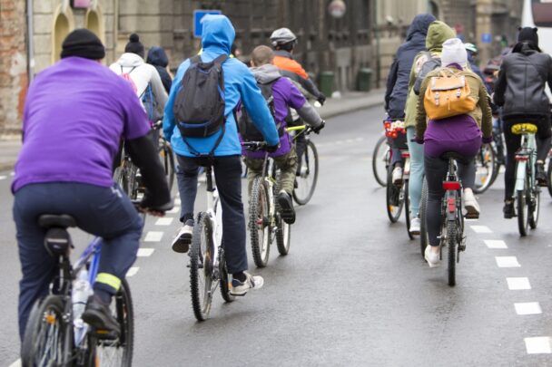 Achteraanzicht van een groepje fietsers wat door een stad een fietstocht maakt.