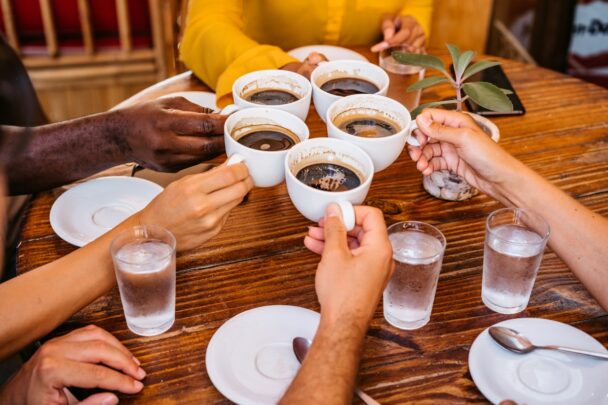 Groepje mensen zit aan tafel en drinkt koffie samen.