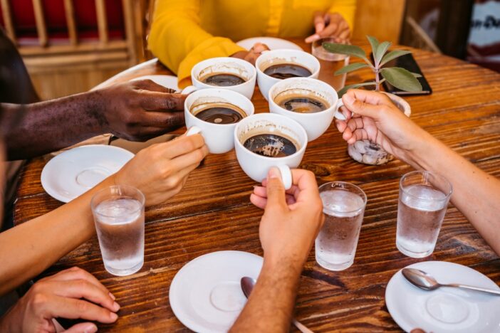 Groepje mensen zit aan tafel en drinkt koffie samen.