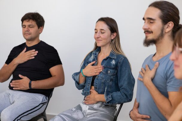 Twee mannen en een vrouw zijn aan het mediteren op een stoel.