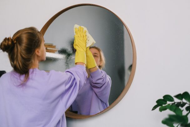 Vrouw maakt een spiegel schoon.