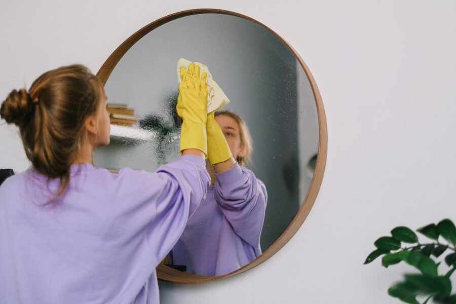 Vrouw maakt een spiegel schoon.