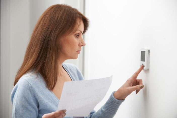 Vrouw zet de thermostaat in huis omlaag.