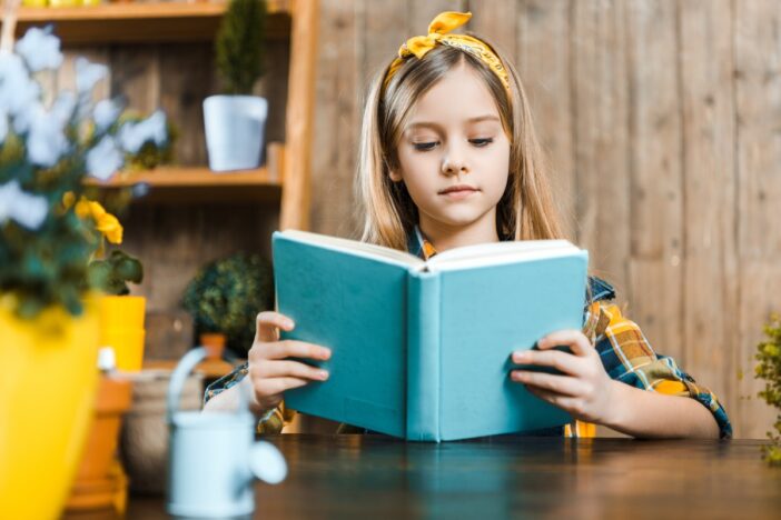 Meisje leest een boek aan tafel.