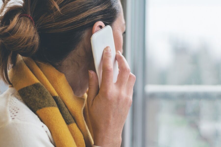 Vrouw telefoneert en kijkt uit raam.