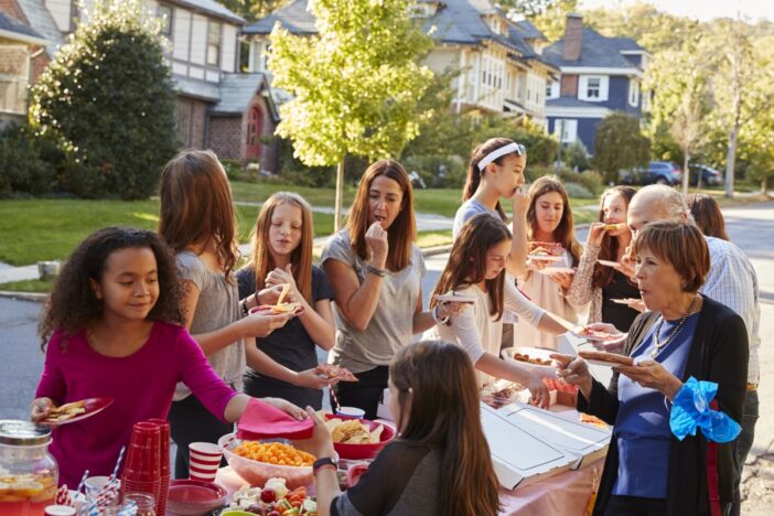 Groepje mensen eet samen op straat aan tafel.