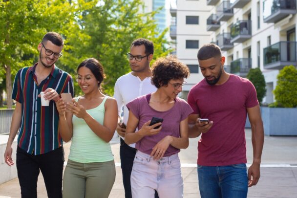 Groepje mensen wandelt samen en maakt gebruik van smartphones.