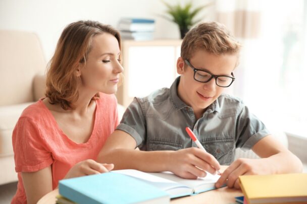 Moeder en zoon zijn samen bezig met schoolwerk.