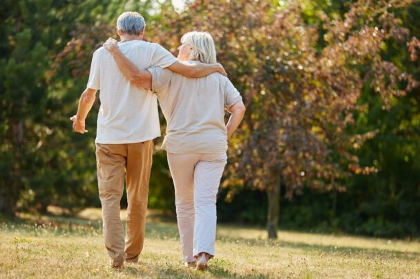 Man en vrouw wandelen samen door gras.