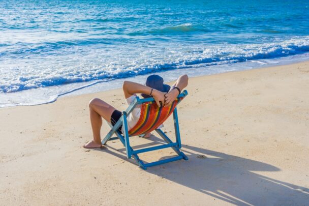 Man ligt ontspannen op een strandstoel aan de kust.