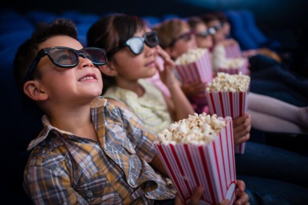 Kinderen met 3d bril en popcorn in een bioscoop.