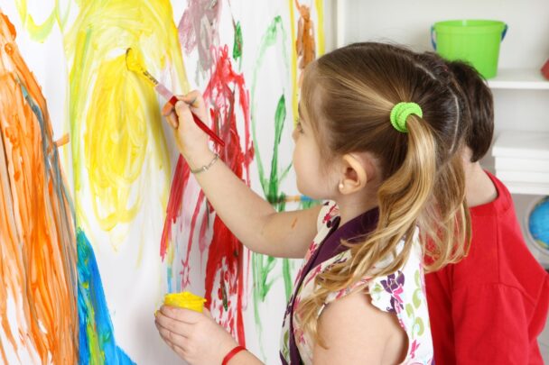 Twee kids zijn aan het schilderen op een muur.