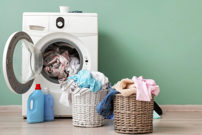 Wasmachine vol met was met twee volle wasmanden ernaast,