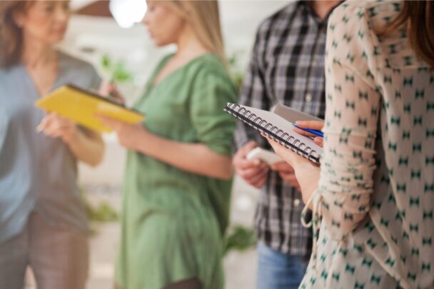 Vrouwen staan in een groepje en houden een notitieblok vast.