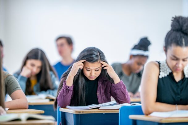 Studenten maken een toets in een schoolsetting. Een meisje oogt duidelijk gestresst.
