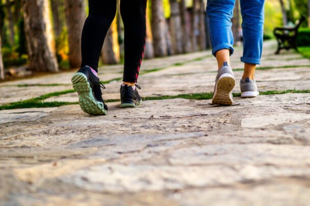 Voeten van twee wandelaars die op stenen pad lopen.