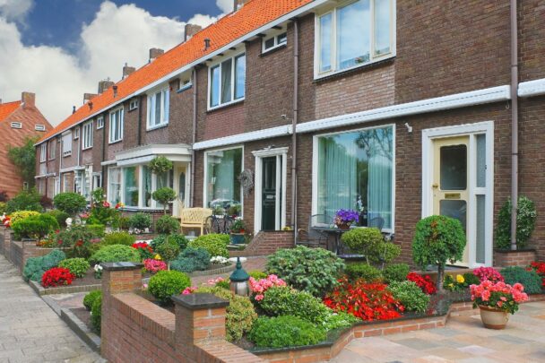 Rijtjes huizen met bloemige voortuinen.