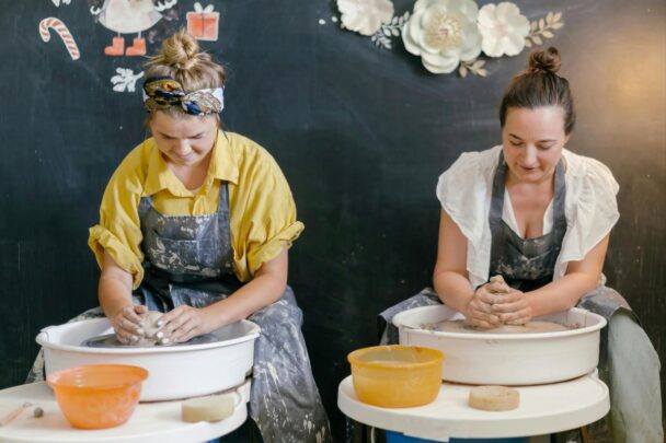Twee vrouwen maken een kunstwerk op een pottenbakkersschijf.