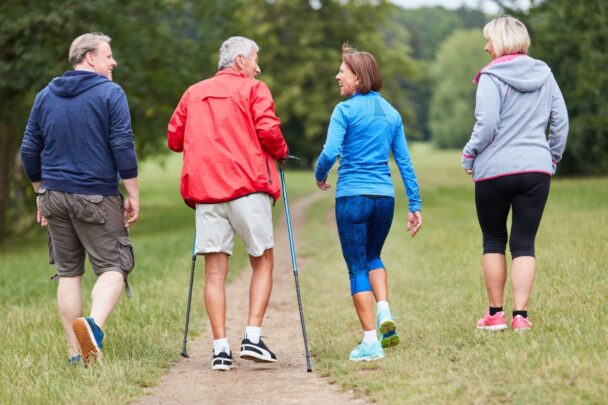 Vier mensen wandelen samen over een pad met gras.