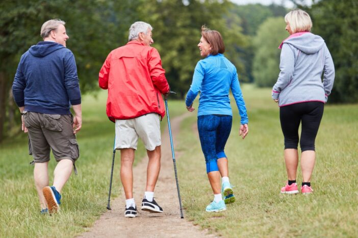 Vier mensen wandelen samen over een pad met gras.