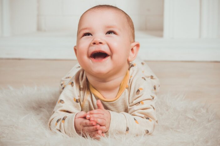 Baby ligt blij lachend op haar buik.