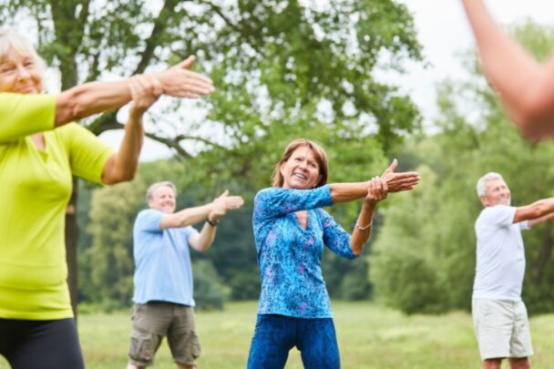 Groepje mensen doet stretchoefeningen in de buitenlucht.