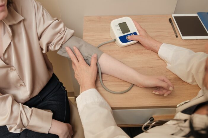 Vrouw laat haar bloeddruk checken door een arts.