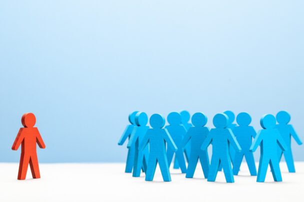 Illustratie van poppetjes die in een groep staan en 1 poppetje buitensluiten.