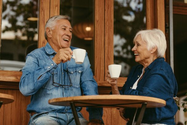 Twee oudere mensen drinken samen koffie op een terrasje.