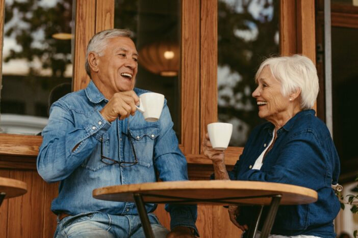 Twee oudere mensen drinken samen koffie op een terrasje.