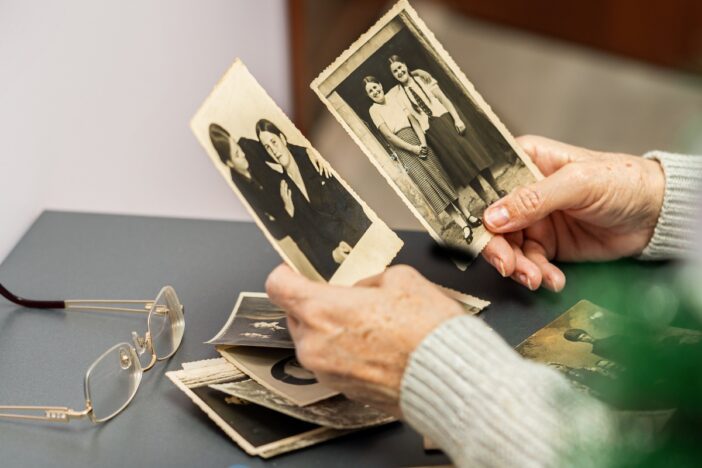 Oudere persoon kijkt naar zwart-wit foto's.