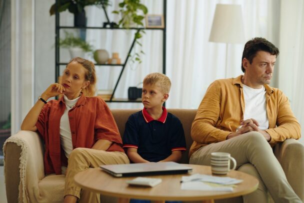 Ouders zitten met ruzie op de bank, met hun zoon er middenin.