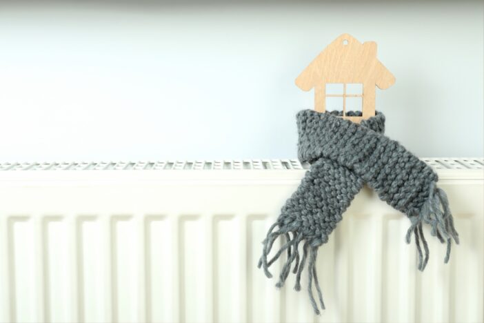 Verwarming met daarop een houten huisje en een sjaaltje.