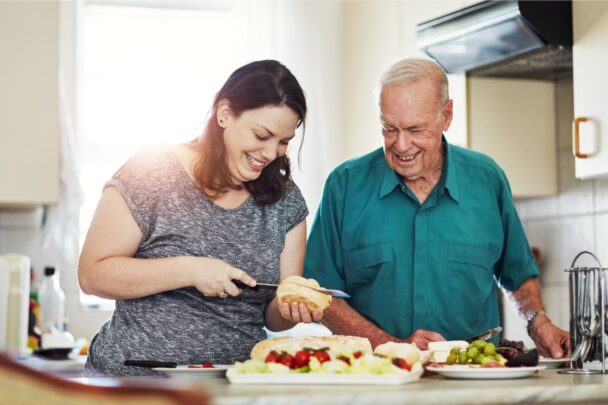 Vrouw maakt een broodje samen met een oudere man.