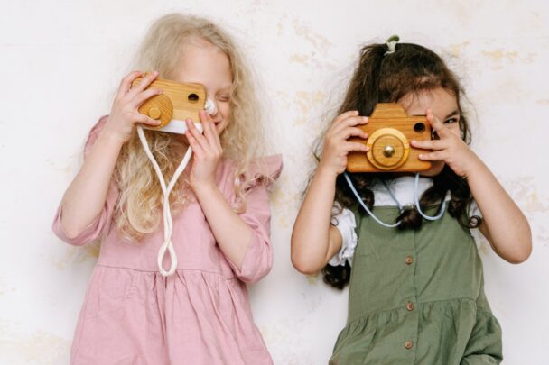 Twee meisjes spelen met houten speelgoed camera's.