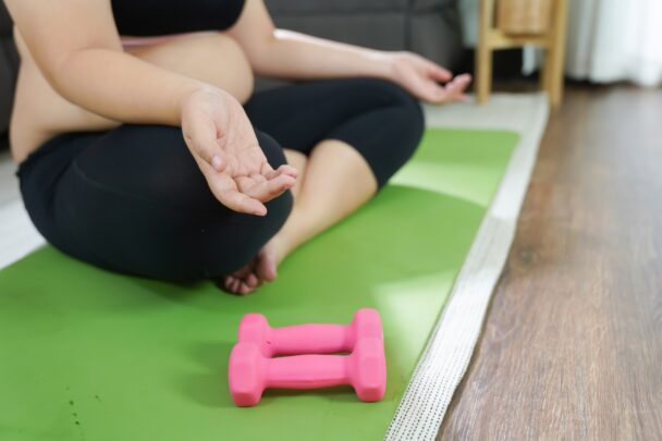 Vrouw is aan het mediteren op een groen sportmatje.