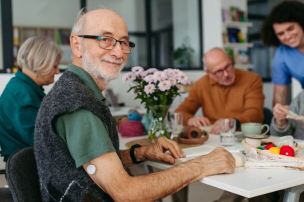 Vier ouderen zitten samen aan tafel in gesprek.