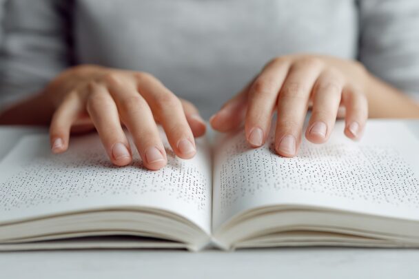 Vrouwenhansden lezen een boek in braille.