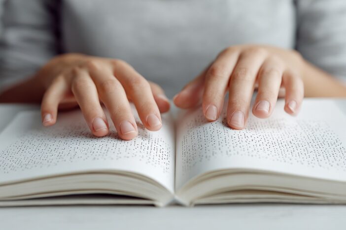 Vrouwenhansden lezen een boek in braille.