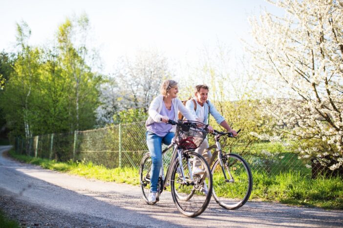 Man en vrouw samen op de fiets in groene omgeving.