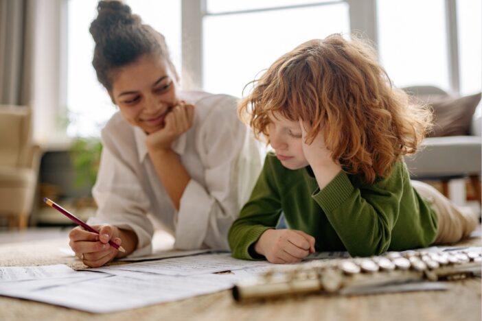 jongetje maakt samen met moeder wat huiswerk op papier.