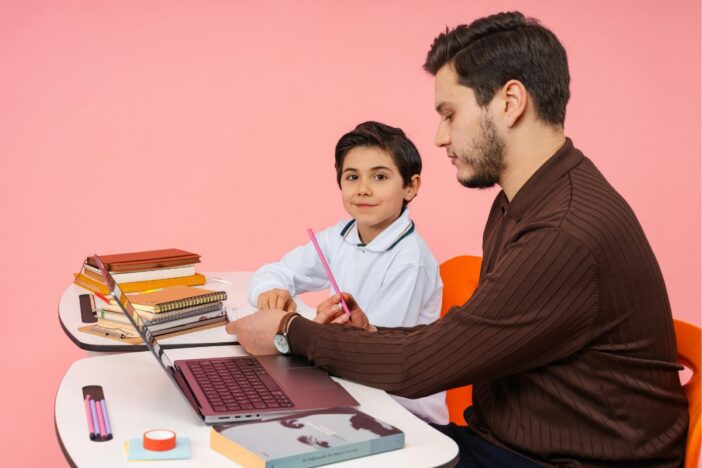 Kind krijgt hulp bij schoolwerk van een jonge man.