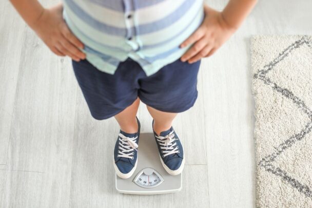 Kind staat op wegschaal om zich te wegen.
