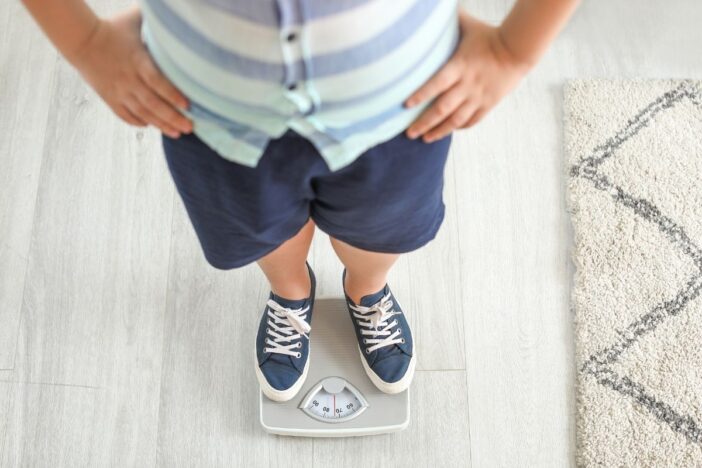 Kind staat op wegschaal om zich te wegen.