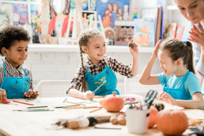 Drie kinderen zijn samen aan het verven en hebben plezier.