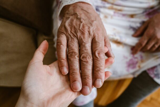 Jonge hand houdt oudere hand voorzichtig vast.