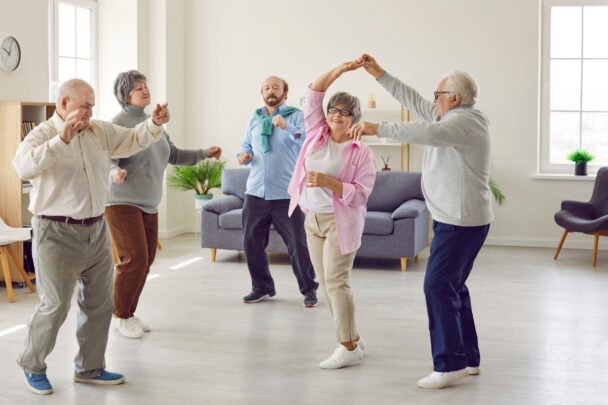 Groepje ouderen is samen aan het danssen en heeft plezier.