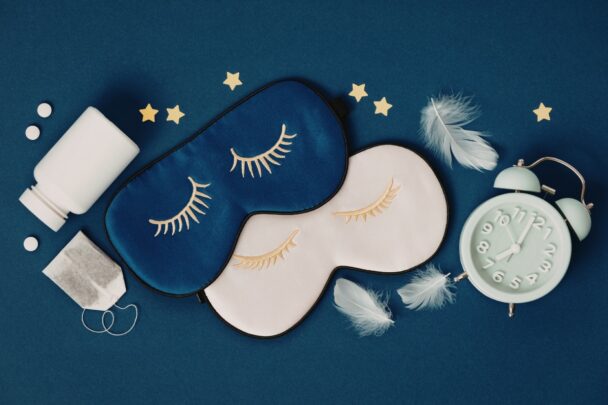 Twee slaapmaskers liggen op een donkerblauwe ondergrond.