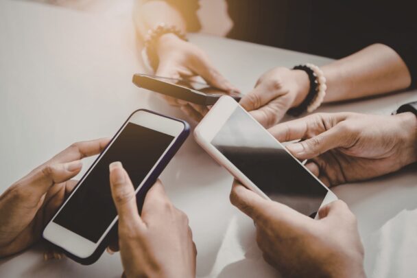 Drie mensen checken samen hun smartphones.